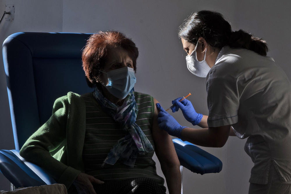 An older women receives a vaccine shot from a medical professional.