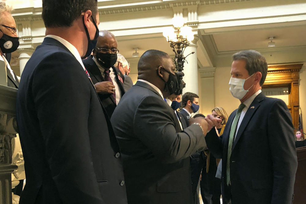 Governor Brian Kemp shakes hands with lawmakers.