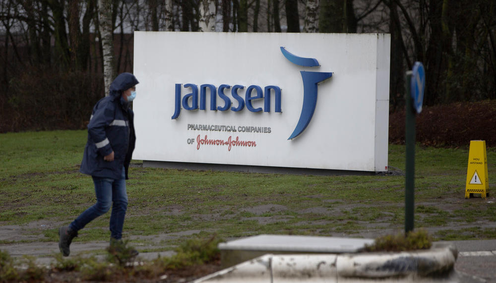 A man walks by a sign outside Johnson & Johnson subsidiary, Janssen Pharmaceutical, in Geel, Belgium, Wednesday, Feb. 3, 2021. 