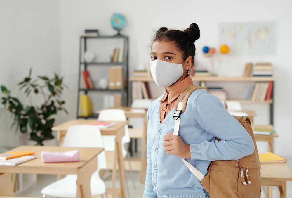 A girl with a backpack wearing a mask