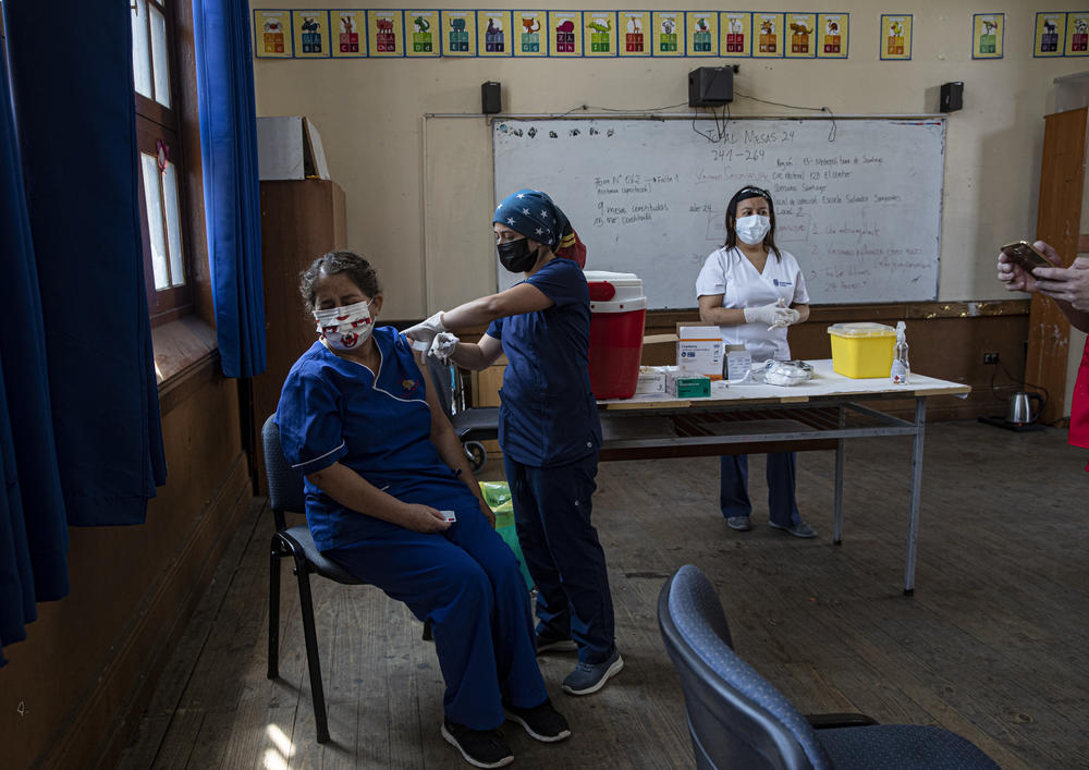 A teacher receieves a COVID-19 vaccine in a classroom in Santiago, Chile.