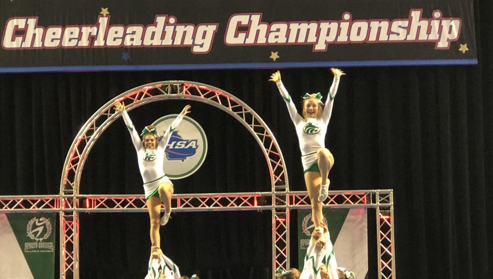 Two cheerleaders being held in the air.