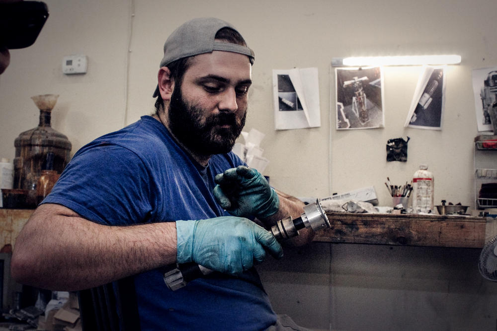 A Vader's Vault employee hand-weathers a lightsaber hilt.