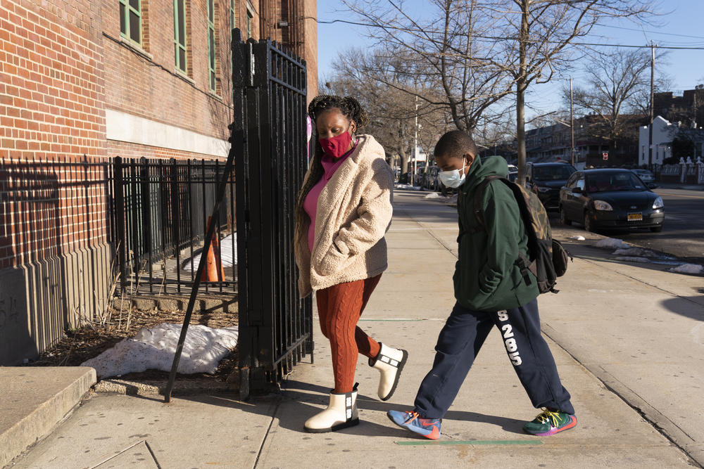 A woman walks her son into a school building.