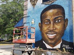 A mural of Ahmaud Arbery graces a wall near the Glynn County Courthouse where three men were indicted for murder in his killing.