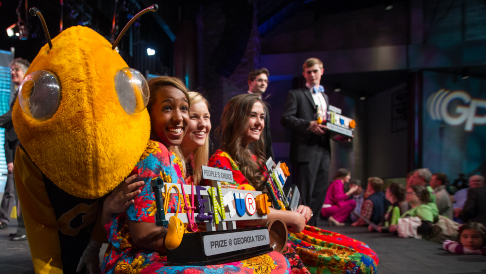 College students sitting on stage with Georgia Tech's mascot.