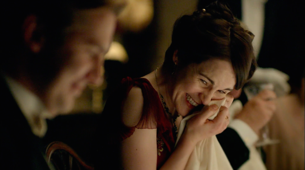 A woman and man laughing at a dinner table.