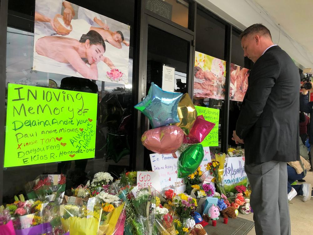 Cherokee County Sheriff Frank Reynolds bows his head after placing a bouquet of flowers outside Young's Asian Massage in Acworth, Ga. Thursday March 18, 2021.