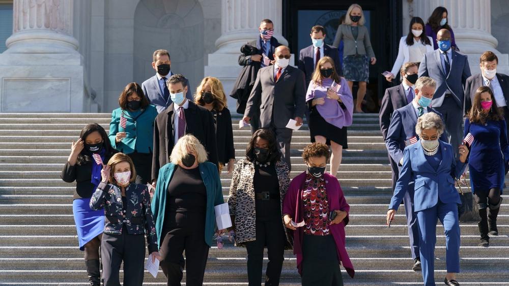 Members of Congress walk down the capitol steps to address journalists.