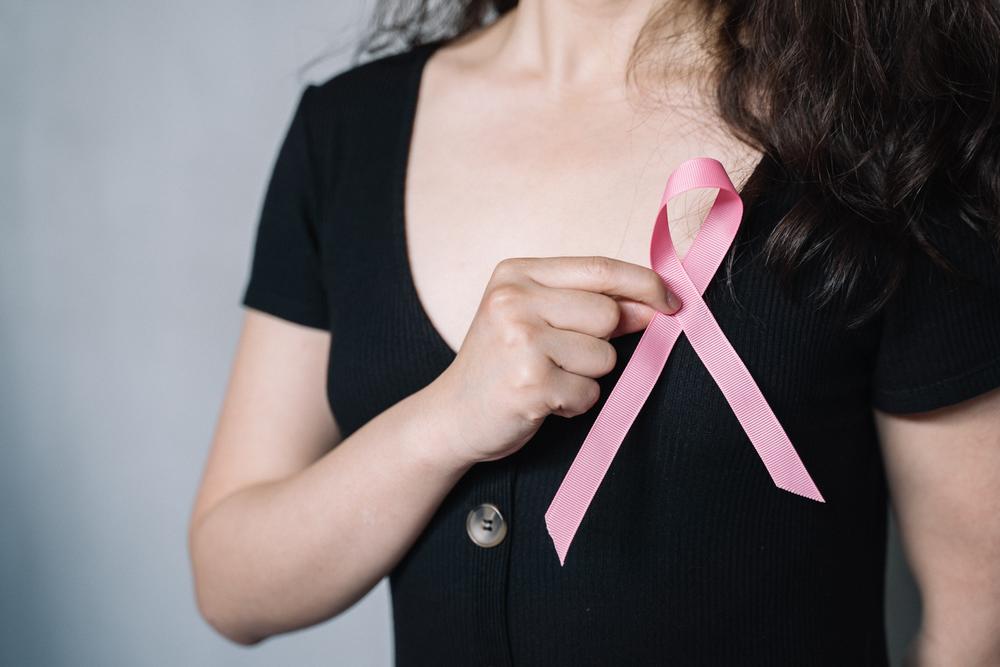 Woman holds pink ribbon to her chest