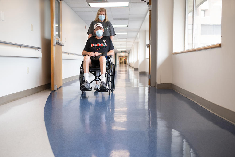 Mark Buchanan of Roopville, Georgia, is wheeled down a hallway by his wife, Melissa, at the University of Florida Health Shands Hospital in January. Buchanan required a double-lung transplant to save his life after contracting COVID-19.