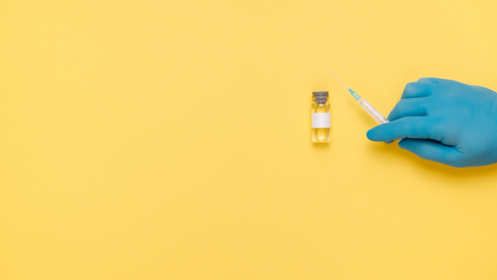 A gloved hand holds a syringe.