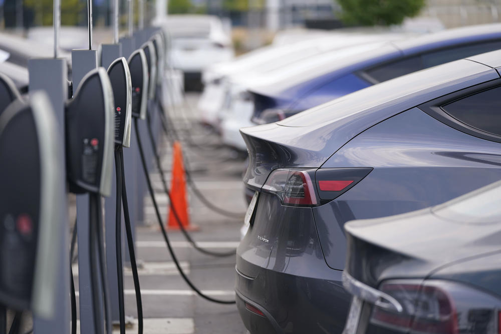 a lineup of Teslas plugged into charging stations