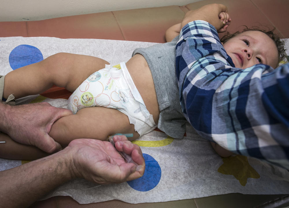 An infant receives a MMR vaccine in the leg.