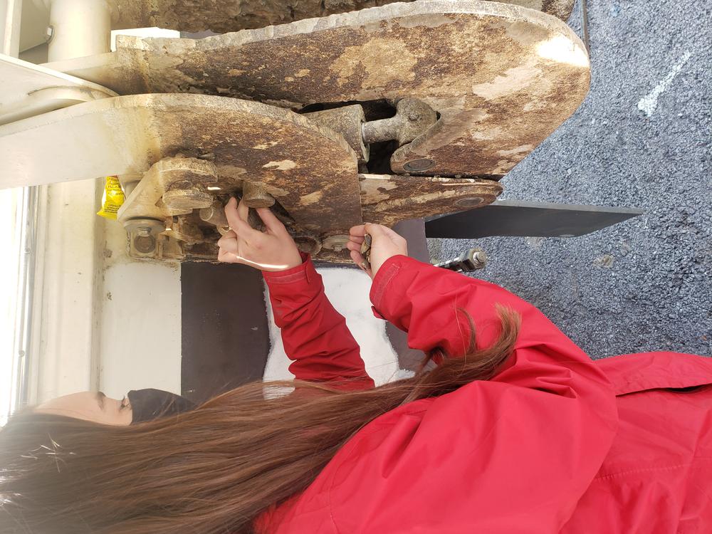a woman cleans invasive zebra mussels off a boat