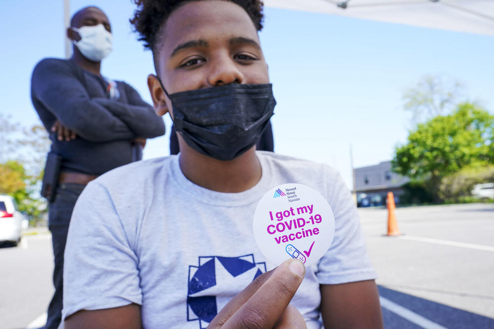 Wilmer Moro, left, watches as his son Wilmer Moro, 13, poses for a photo with his vaccination sticker after being inoculated with the first dose of the Pfizer COVID-19 vaccine ain Freeport, NY on May 14.