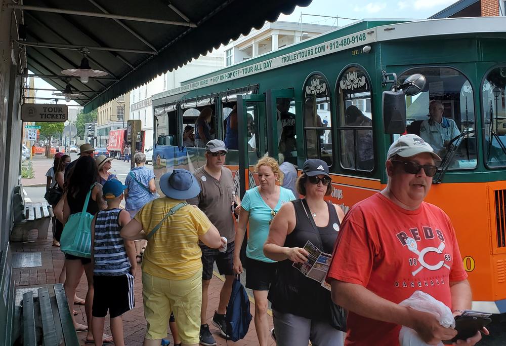 People disembarking from a tourist trolley while others wait to board