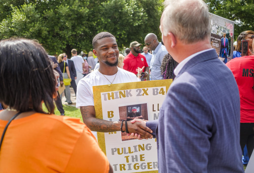 Shandarius Hillman shakes hands with Macon-Bibb County Mayor Lester Miller after Miller made public a plan to push back against rising rates of killing the city. Hillman's brother was killed in May. 