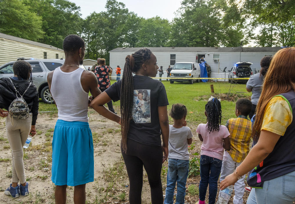 Family and neighbors of Quinterious Hillman and Jerod Lester watch as Bibb County Sheriff's Deputies investigate the scene of Hillman and Lester's killing in May.