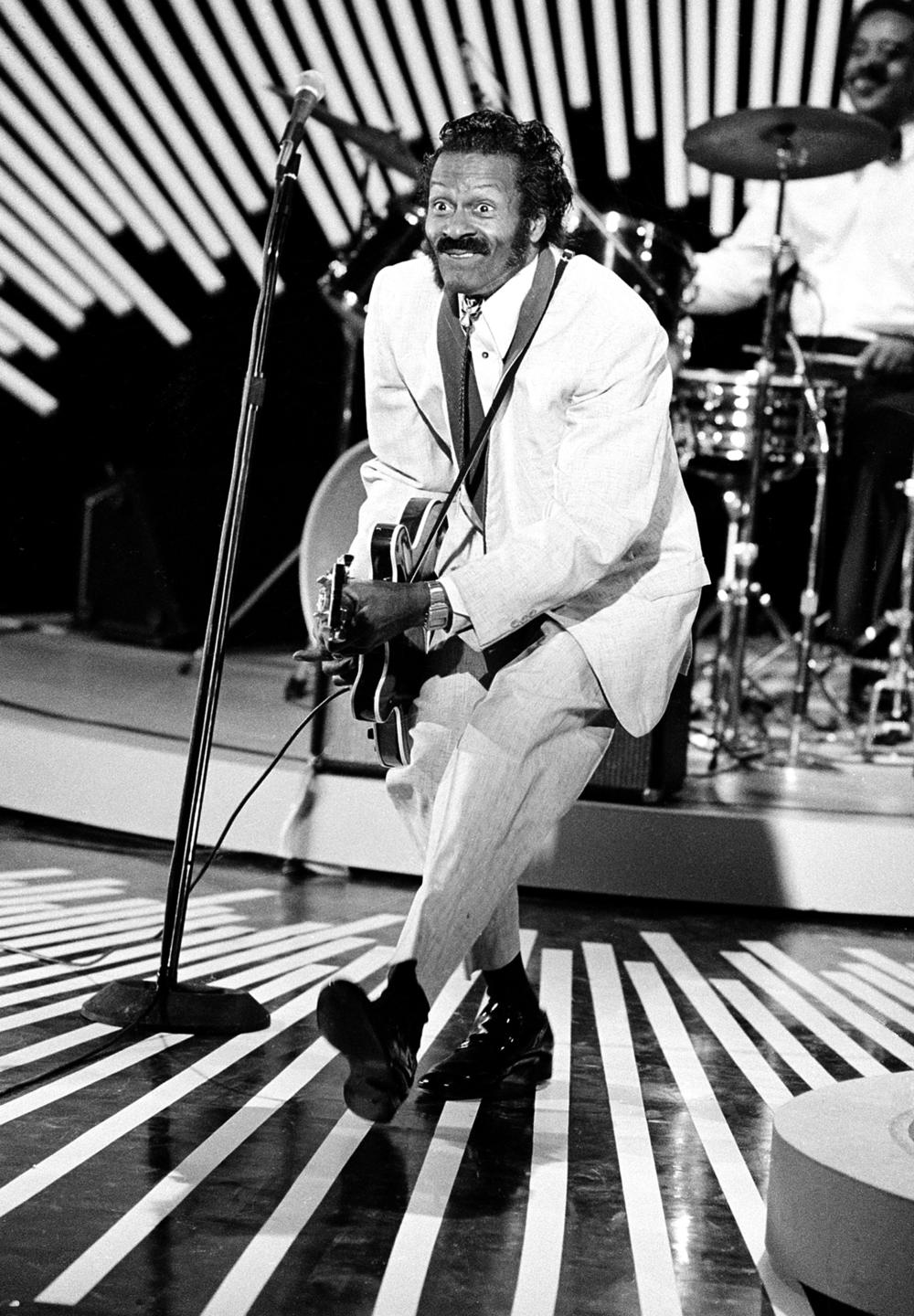 American guitarist and singer Chuck Berry performs his "duck walk" on stage as he plays his guitar on April 4, 1980. The location is not known.