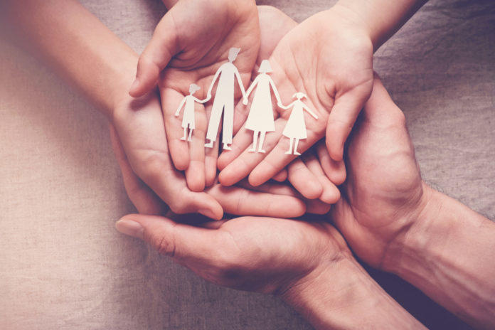 Stock image of cut out of family in enclosed hands