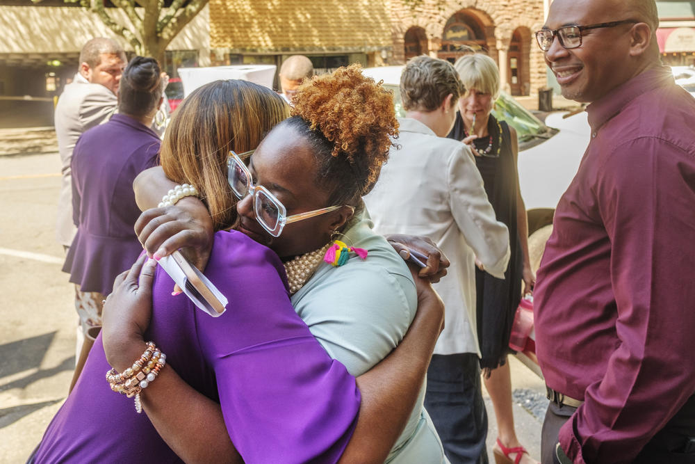 Anissa Jones, center, hugs her friend Shanita Davis after a press conference about the lending program helping Jones and her husband Deon Aiken, right, purchase a building in downtown Macon. 