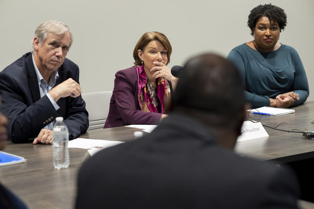 Sen. Jeff Merkley, left, D-Ore.; Sen. Amy Klobuchar, D-Minn., and former Georgia state Rep. Stacey Abrams, right, listen to people talk about their experiences in voting, in Smyrna, Ga., Sunday, July 18, 2021.