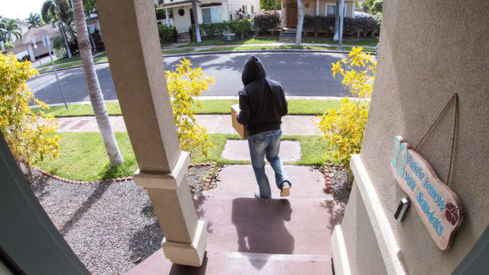 Unidentified person takes a package from a porch