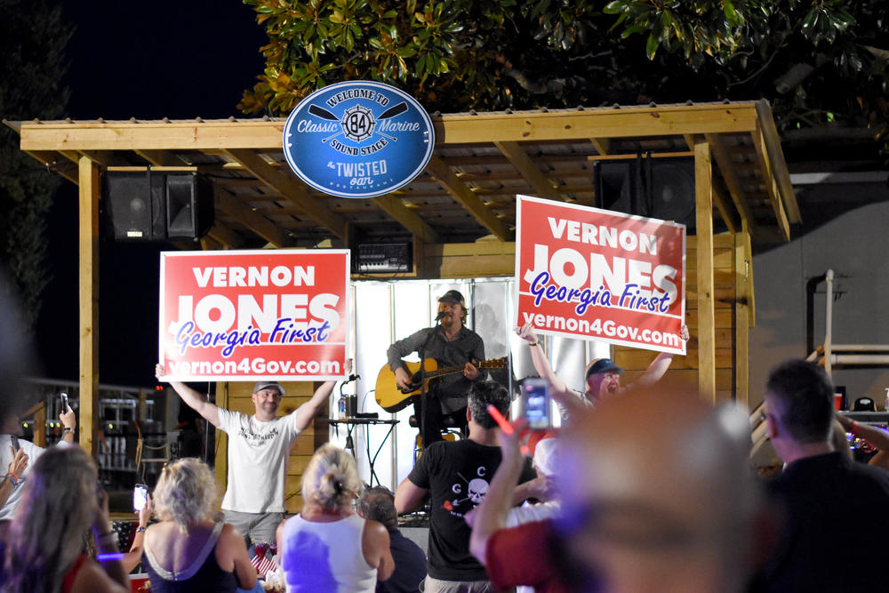 Vernon Jones supporters hold signs while country music star Travis Tritt performs at a fundraiser for the GOP gubernatorial candidate.