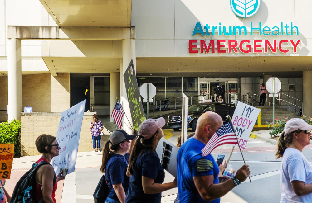 Protesters against the vaccine mandate for employees of the Medical Center at Atrium Health in Macon march by the hospital emergency room entrance on Saturday, August 14. Only a fraction of the about 100 protesters were Medical Center employees. 