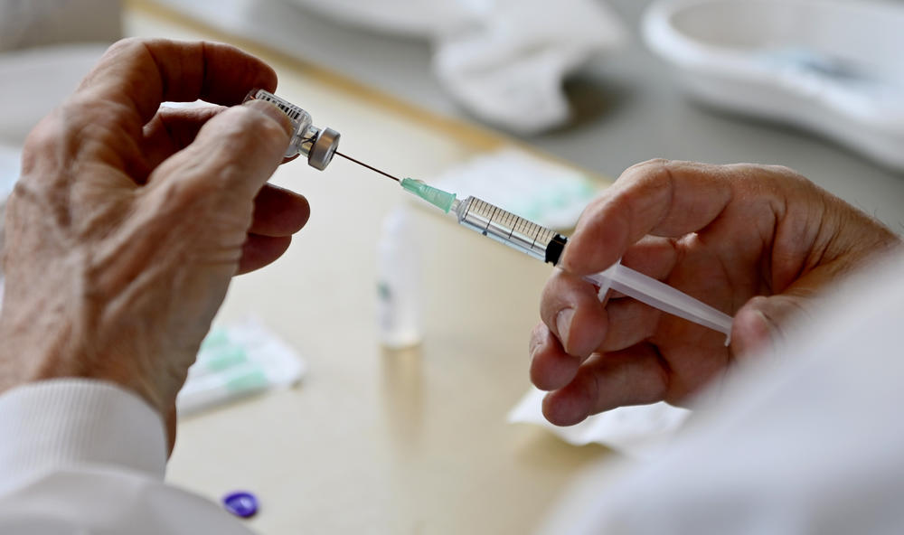 A vaccine shot held by a medical professional.
