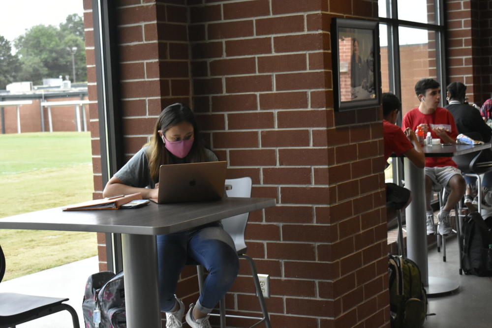  A masked Forsyth Central High School studies on her laptop during her lunch break in this 2020 file photo. School districts are taking a variety of approaches to high numbers of COVID-19 cases among children. 