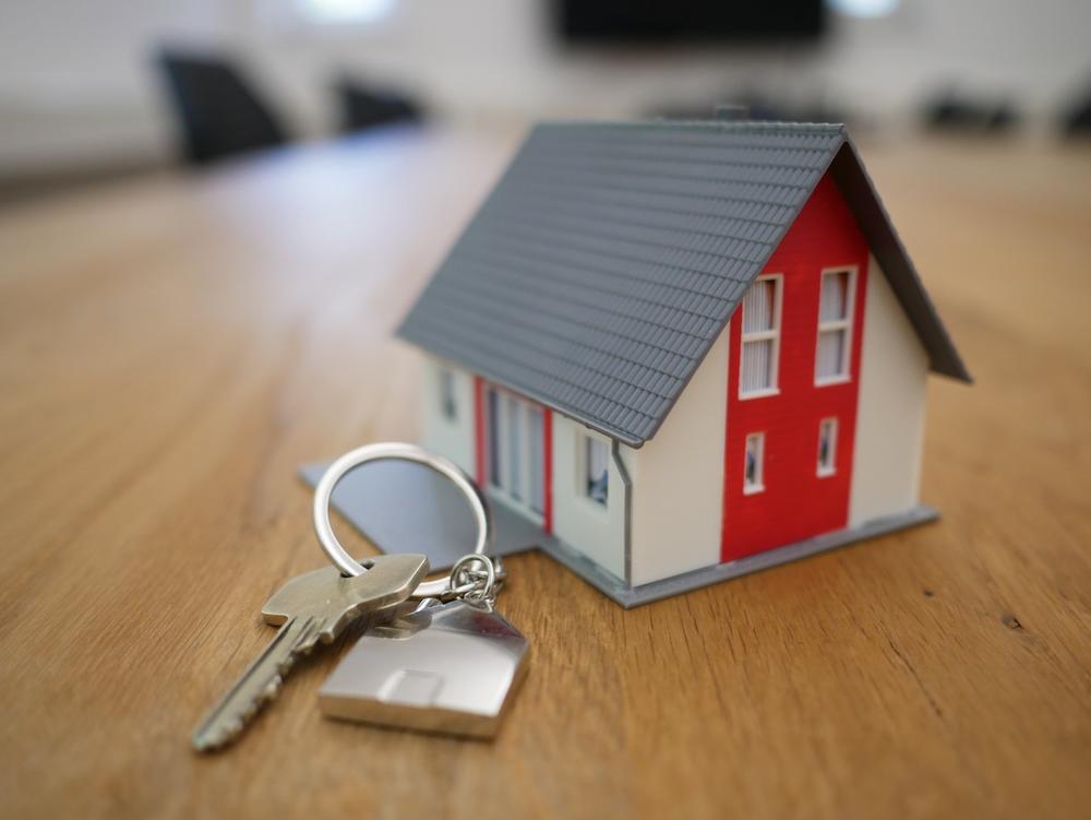 A photo of a house key next to a miniature house