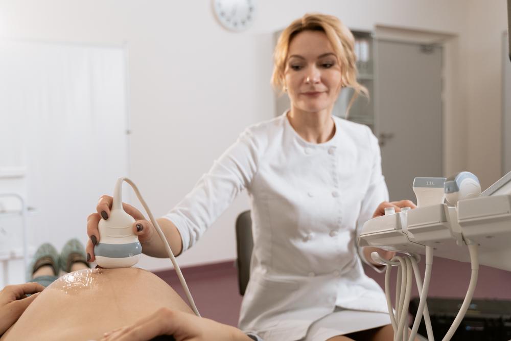 A nurse conducts an ultrasound on a pregnant person