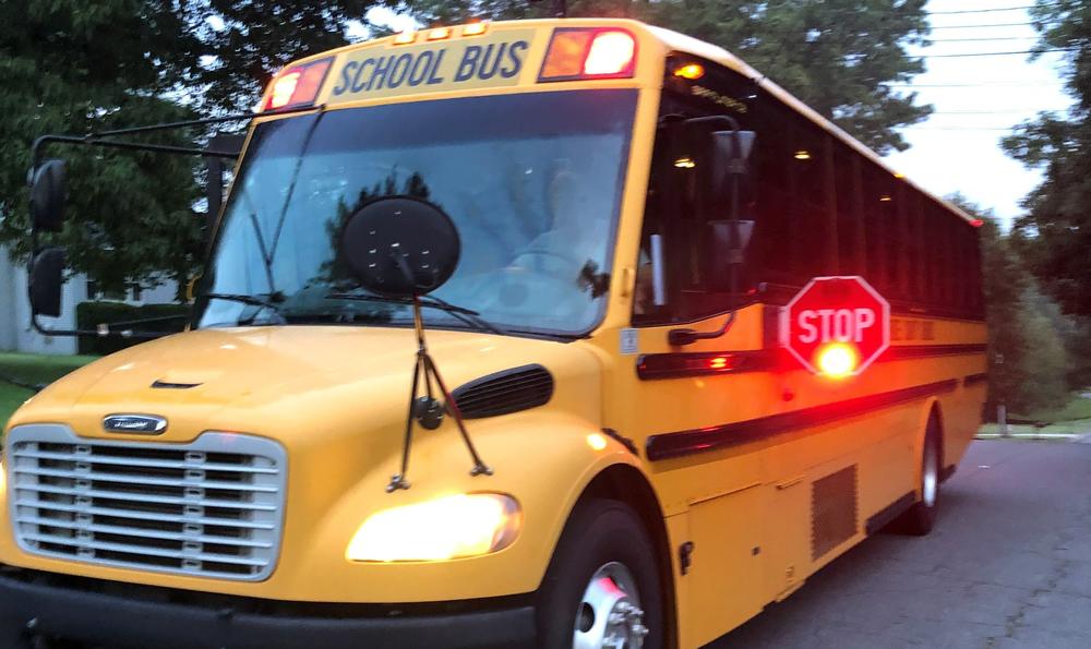 A school bus with its stop sign closing