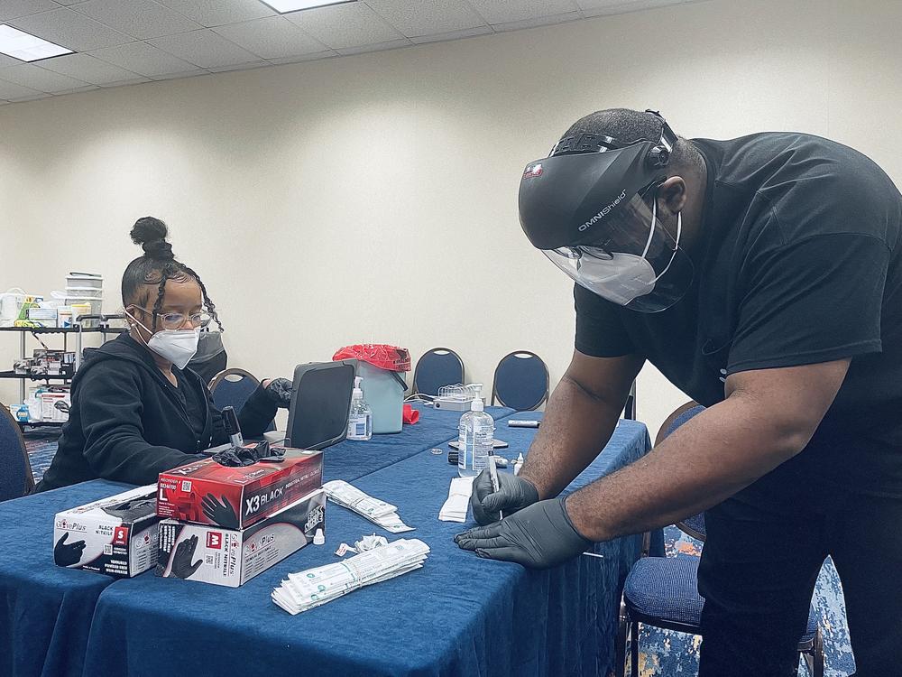 Viral Solutions medical assistants Dorian Lambert and Mulea Wambua prepare COVID-19 tests at Dragon Con 2021.