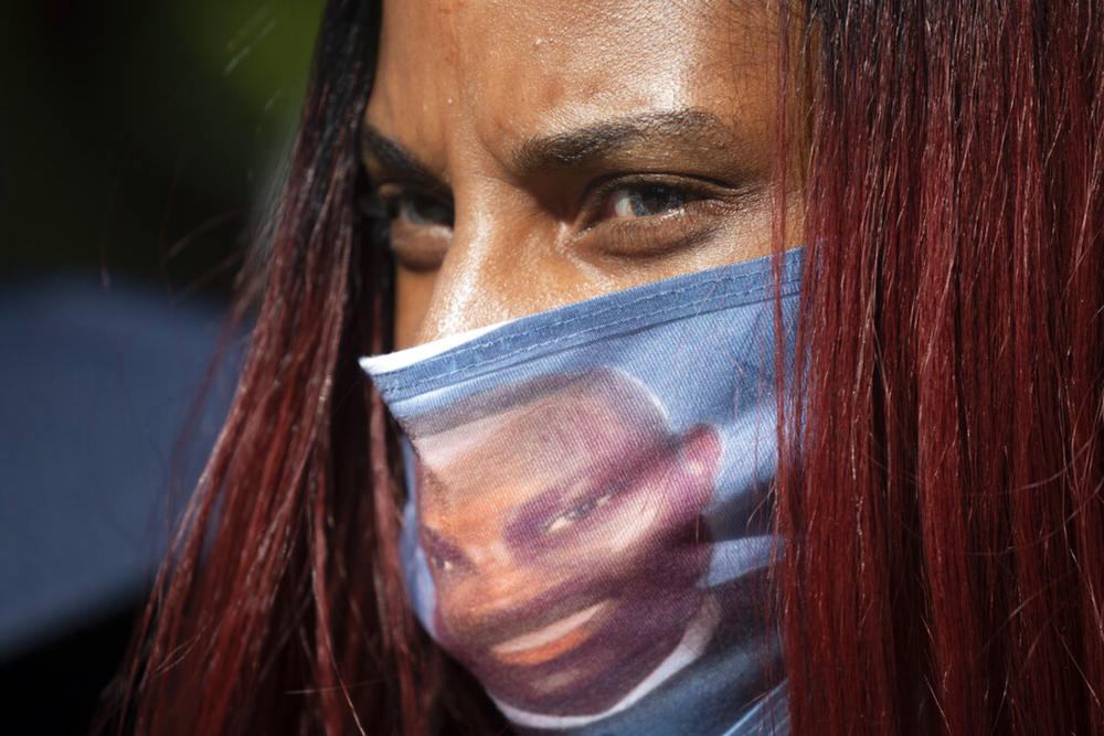 A woman wears a face covering with the likeness of shooting victim Ahmaud Arbery printed on it during a rally May 8, 2020, in Brunswick, Ga., to protest Arbery's February 2020 killing.