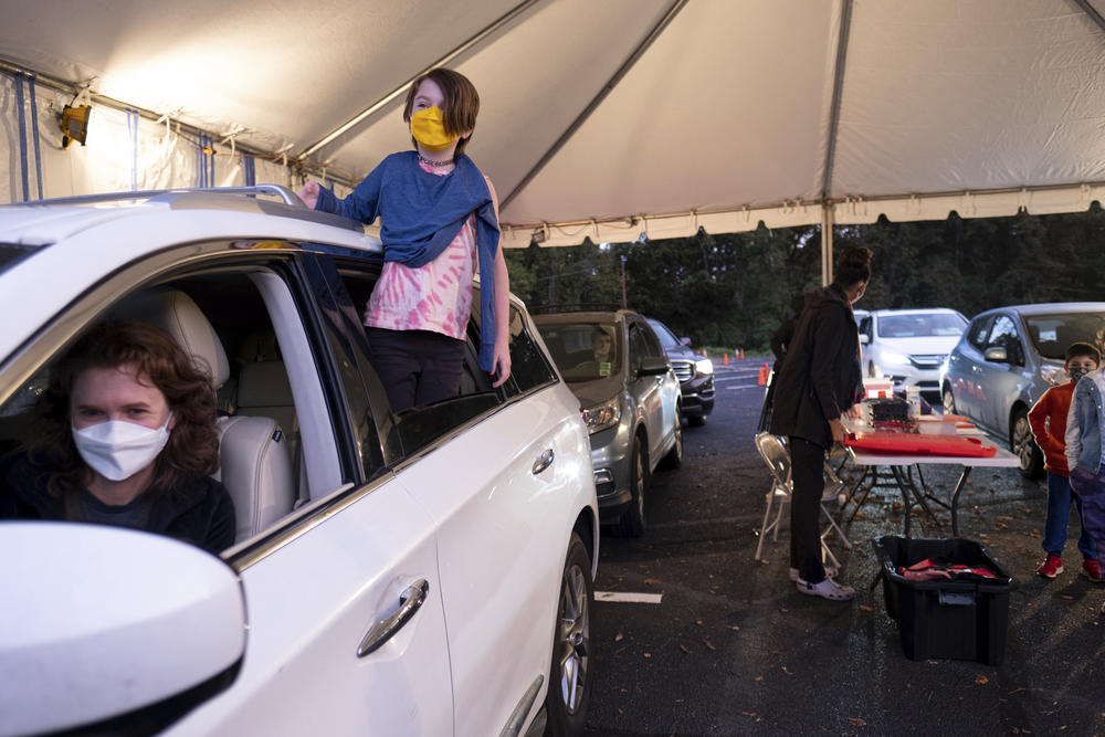 Cate Zeigler-Amon, 10, hangs out of the car as she waits with her mother, Sara Zeigler, to receive her first dose of COVID-19 vaccine at the Viral Solutions vaccination and testing site in Decatur, Ga. on Wednesday, Nov. 3, 2021. 