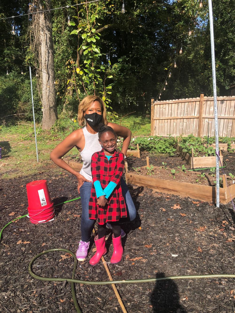 Morning Edition host Leah Fleming poses with Kendall Johnson, the youngest USDA-certified farmer in Georgia, at the 6-year-old's growing farm in Southwest Atlanta in autumn 2021.