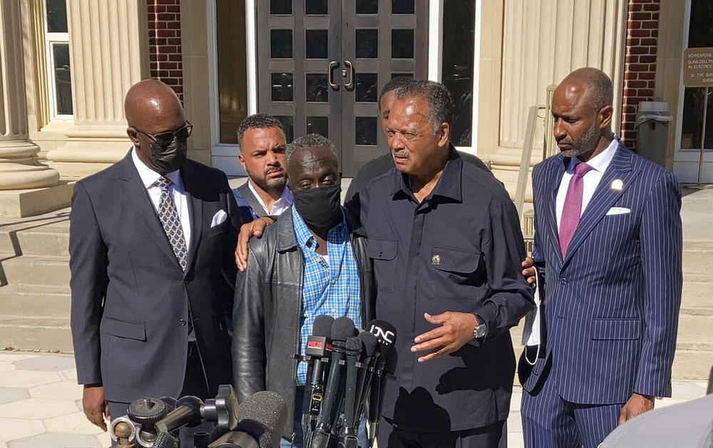 The Rev. Jesse Jackson, center right, puts his arm around Ahmaud Arbery's father, Marcus, in a news conference during a break of the trial of three men charged with killing Arbery taking place at the Glynn County courthouse in Brunswick, Georgia, on Tuesday, Nov. 16, 2021. A judge denied a defense attorney's request to kick Jackson out of the courtroom.