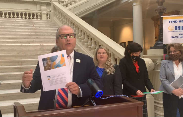 Jeff Breedlove holds a printed copy of the Georgia Mental Health Policy Partnership's Unified Vision for Transforming Mental Health and Substance Use Care in Georgia.