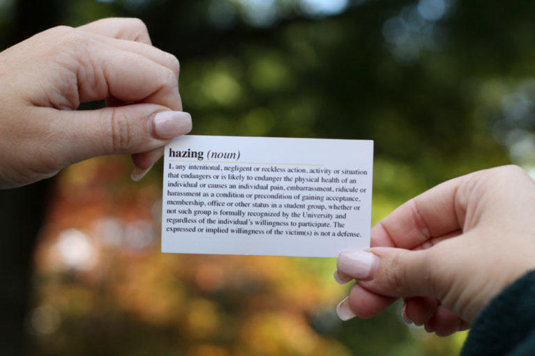 A student at Kennesaw State University holds an anti-hazing resource card from the Office of Fraternity and Sorority Life. 