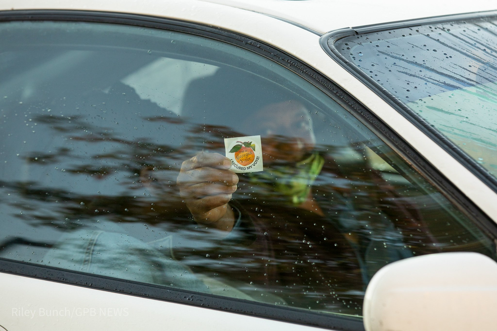 A voter in Atlanta holds up their sticker.