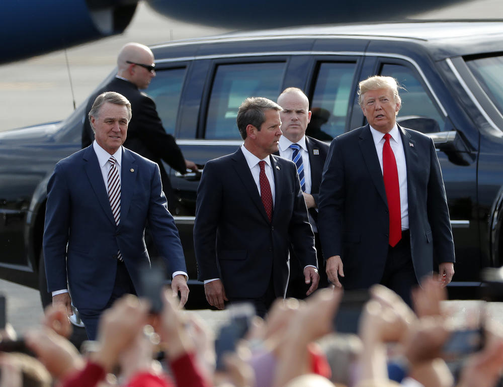 Georgia Republican gubernatorial candidate Brian Kemp, center, walks with President Donald Trump, right, and Sen. David Perdue (R-Ga) as Trump arrives for a rally Sunday, Nov. 4, 2018, in Macon, Ga.