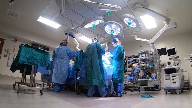 Surgeons operating in blue scrubs.