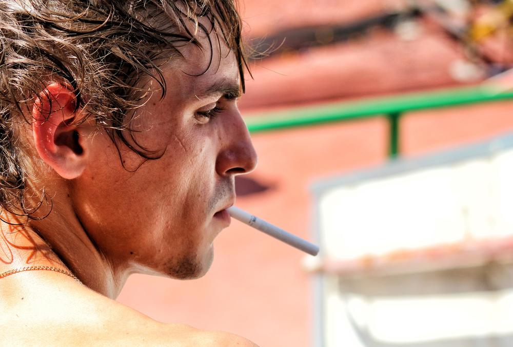 Close up of man's face with an unlit cigarette in his mouth