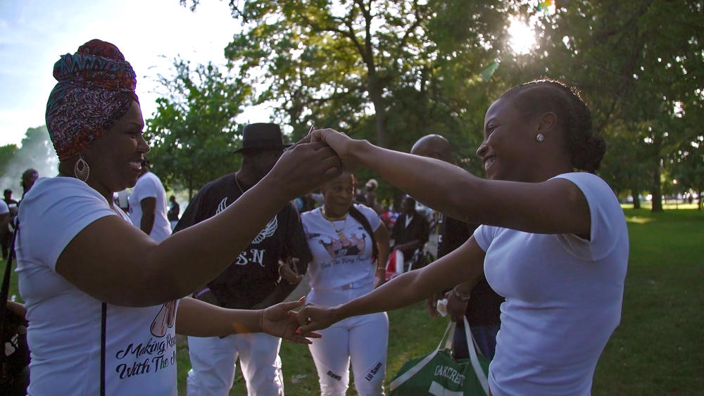 Two women in a park holding hands and dancing.