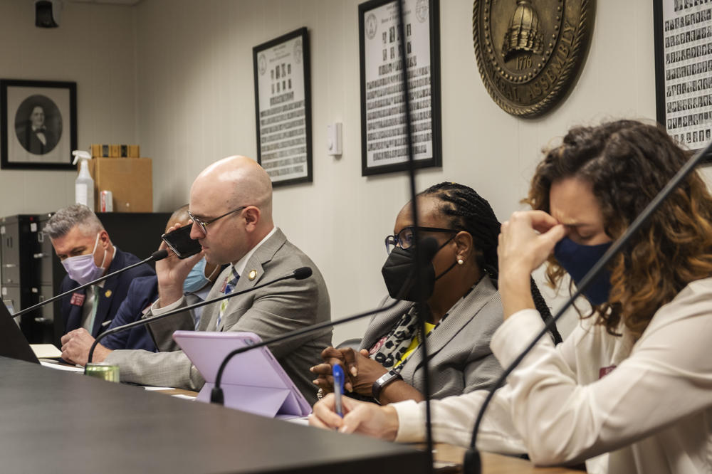 Georgia State House Member John McLaurin holds his phone to a conference room microphone so fellow members of an ad hoc committee of house members can hear the testimony of a correctional officer at Lee Arrendale State Prison in September 2021. 