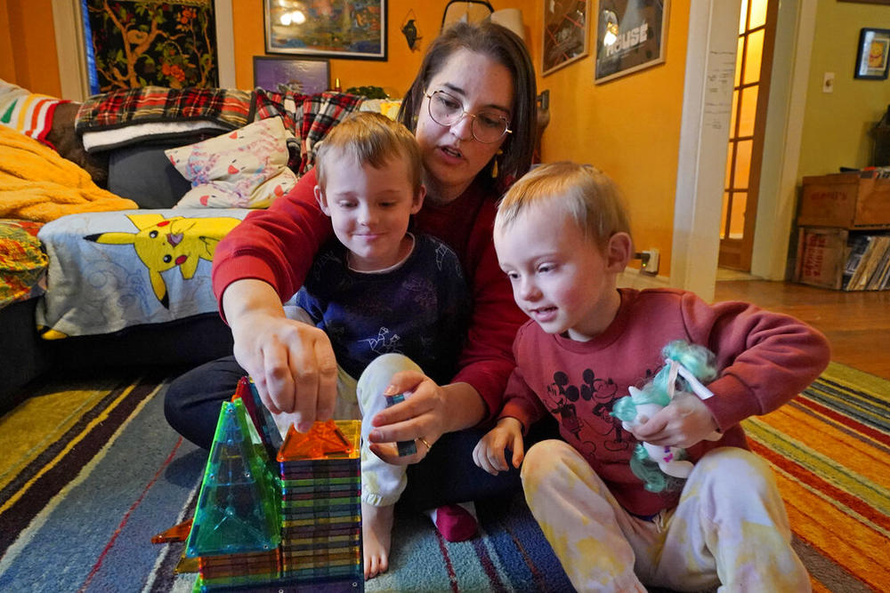 mother holding a child and sitting next to a second child