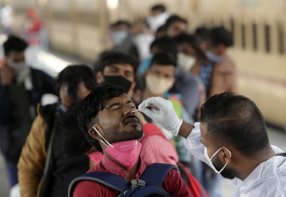 A health worker collects a swab sample from a traveler at a railway station to test for COVID-19, before he is allowed entry into the city, in Mumbai, India, Tuesday, Jan. 4, 2022. 